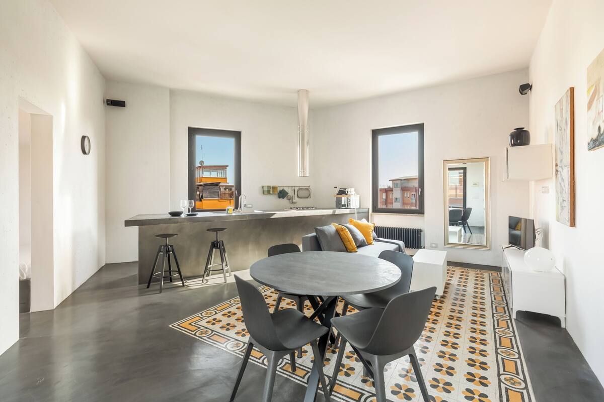 A modern kitchen with a central island, bar stools, and a dining area with a round table and chairs.