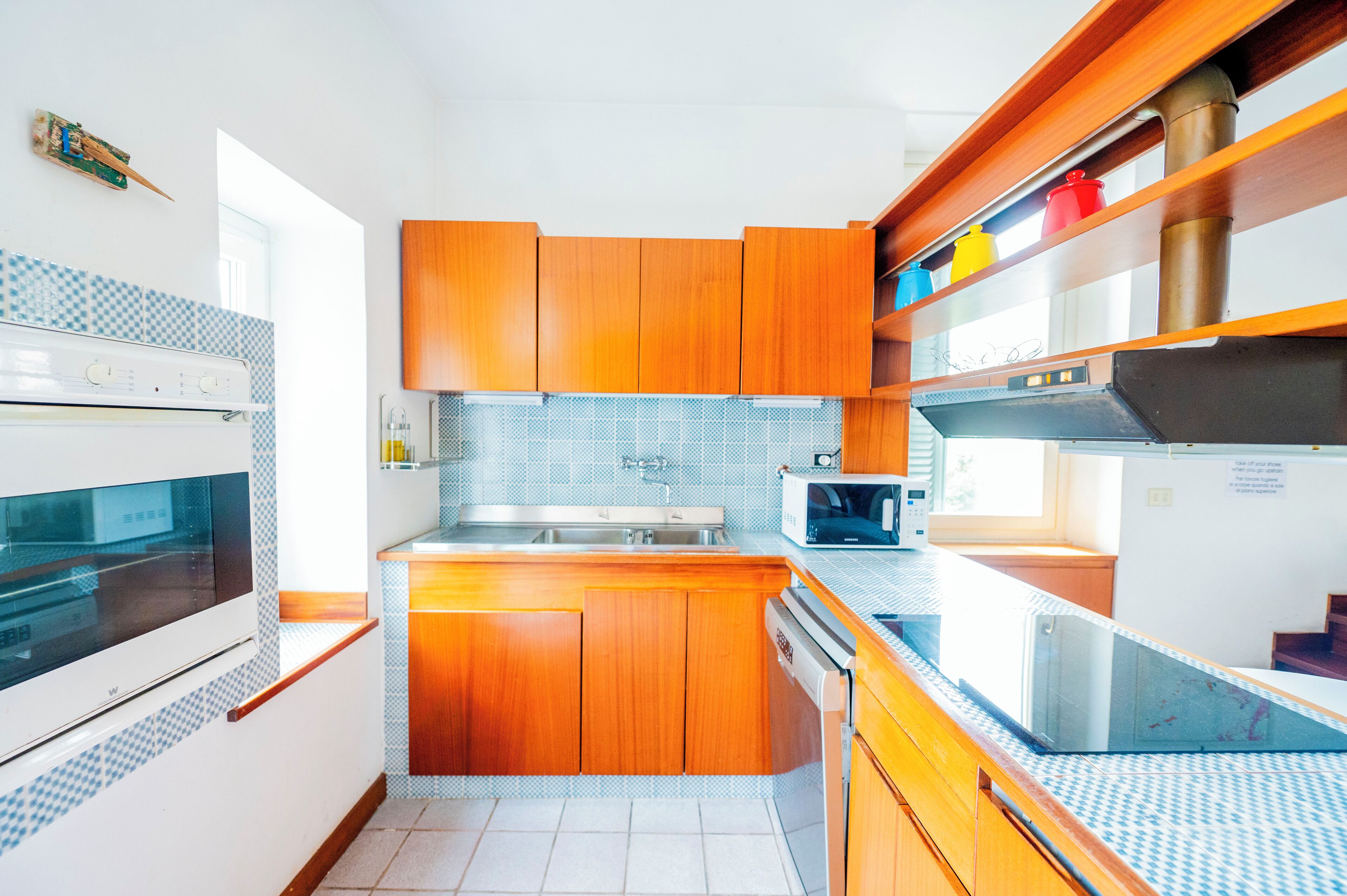 A modern kitchen with wooden cabinets, a stainless steel sink, and a microwave.