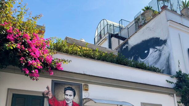 A building with a mural of a man in a red shirt, a green door, and a balcony with plants. - Lovely Apartment In Hip And Vibrant Pigneto (Rome)