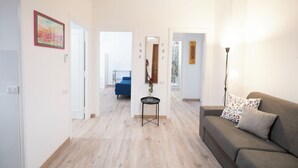 A living room with a sofa, a small table with a vase, and a blue couch in the background. - Lovely Apartment In Hip And Vibrant Pigneto (Rome)