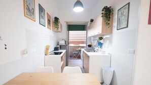 A compact kitchen with a dining table, white cabinets, and a view to the living area. - Lovely Apartment In Hip And Vibrant Pigneto (Rome)