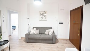 A living room with a grey sofa, patterned cushions, a pendant light, and a framed artwork on the wall. - Lovely Apartment In Hip And Vibrant Pigneto (Rome)