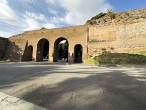 A large brick structure with three arches and a road in front.