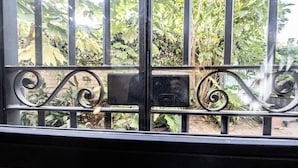 A metal gate with decorative scrollwork, set against a backdrop of lush greenery.