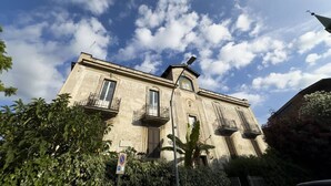 A historic building with a classic architectural style, featuring a prominent central tower and multiple balconies.