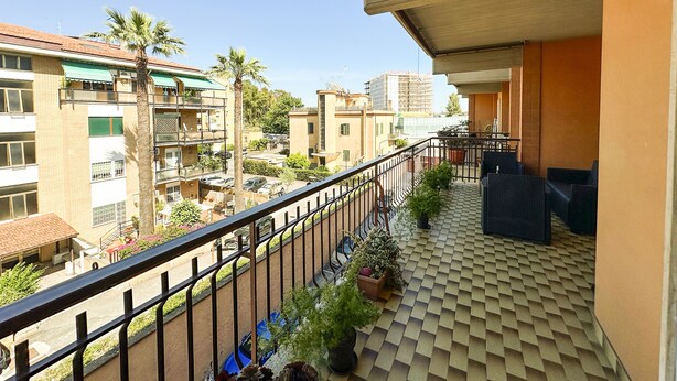 A balcony with a tiled floor, potted plants, and a view of surrounding buildings. - Luminous 2Br Family Apartment In Residential Area  (Rome)
