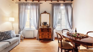 A room with a wooden ceiling, a sofa, a dresser, a table with chairs, and a mirror. - Monti  Apartments (Rome)