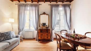 Una stanza con soffitto in legno, un divano, una cassettiera, un tavolo con sedie e uno specchio.