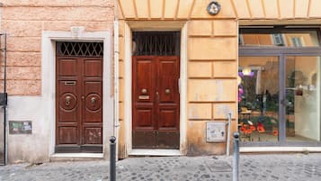 Facciata di un edificio con due porte in legno, una finestra con vetrina e una strada acciottolata.