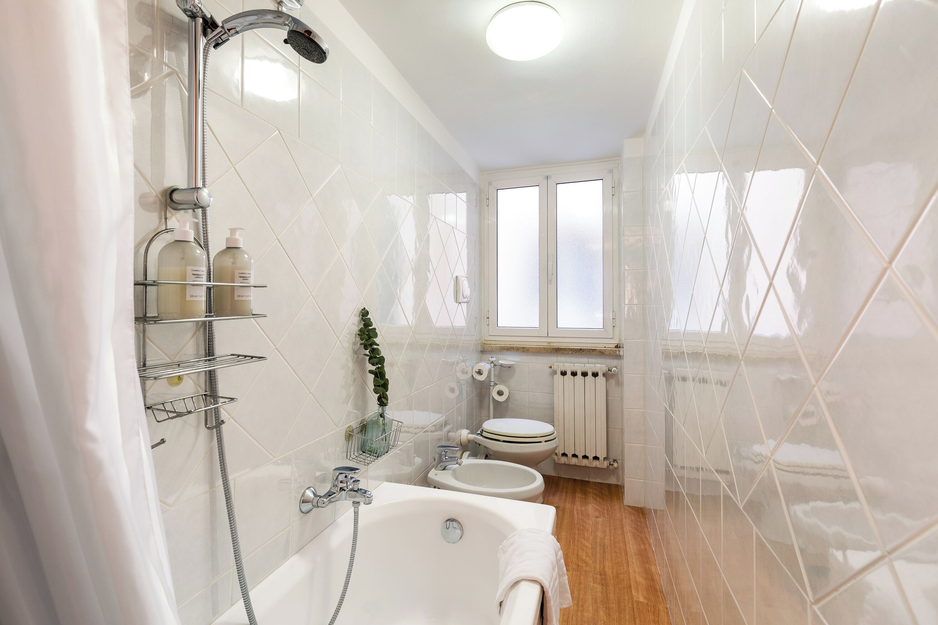A bathroom with a bathtub, a shower, a toilet, and a window.