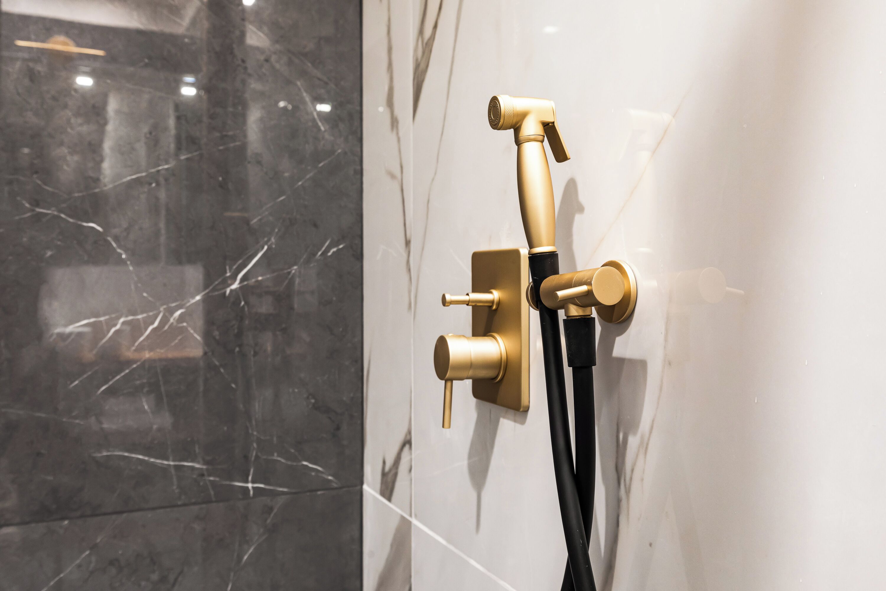 A gold showerhead mounted on a wall with a marble pattern.