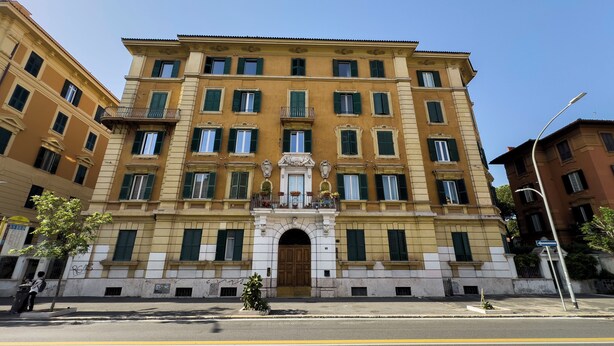 Un edificio de varios pisos con una entrada central, ventanas amplias y una fachada simétrica.