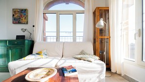Una habitación acogedora con una cama, una mesa de madera con un libro, una lámpara y vistas al exterior.