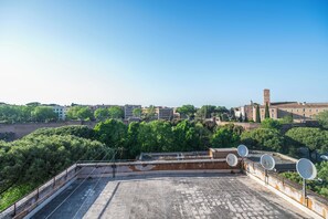 Une terrasse sur le toit, dotée d’antennes paraboliques, qui offre une vue panoramique sur la ville, avec ses bâtiments et ses espaces verts.
