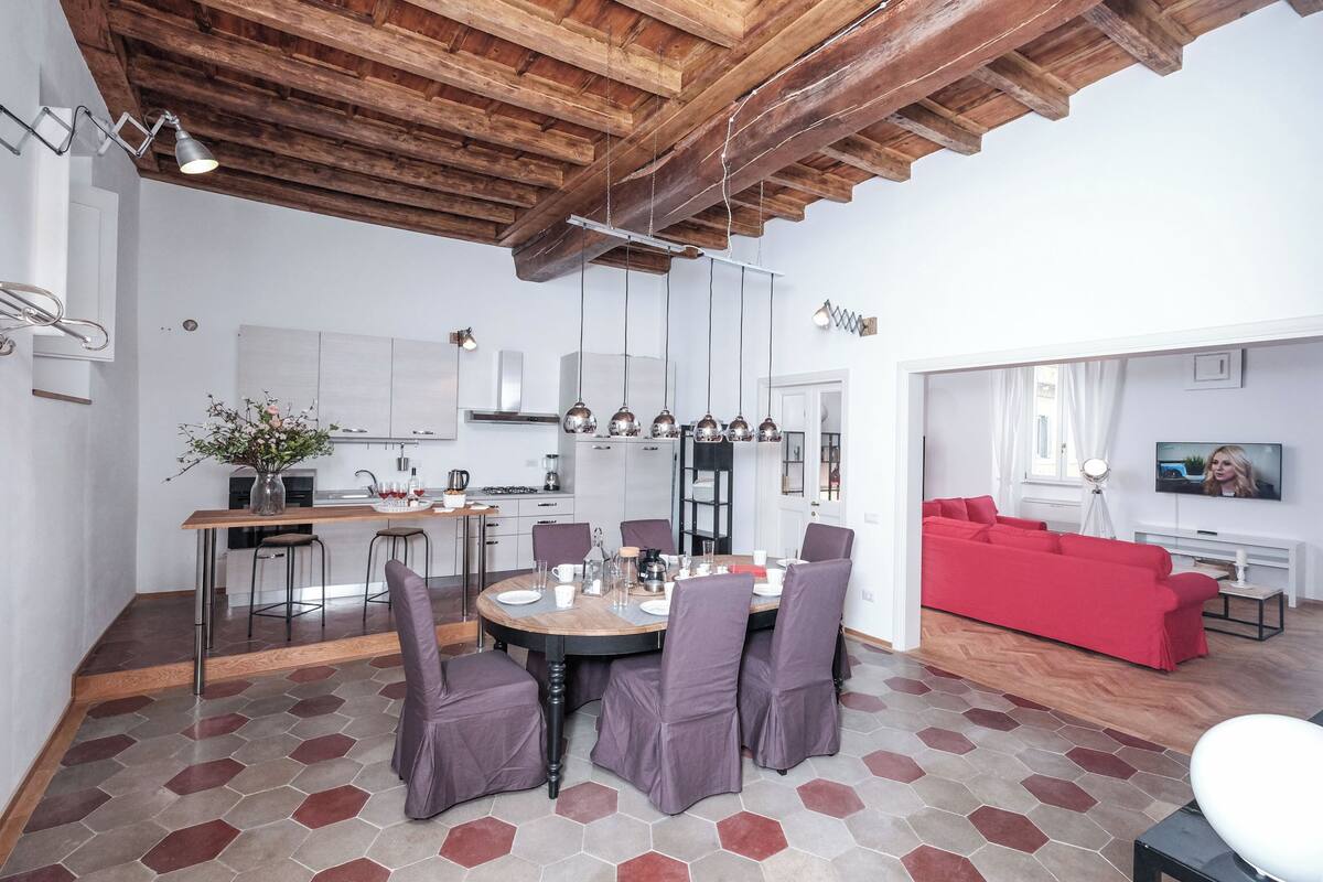 A modern living space with a dining area, kitchen, and a red sofa in the living room.