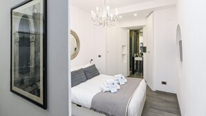 Un dormitorio moderno con una cama grande, una araña, un espejo y un cuadro en la pared.