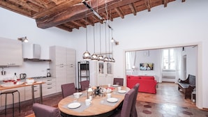 Una cocina moderna con comedor, que incluye una mesa de madera, sillas e iluminación colgante.