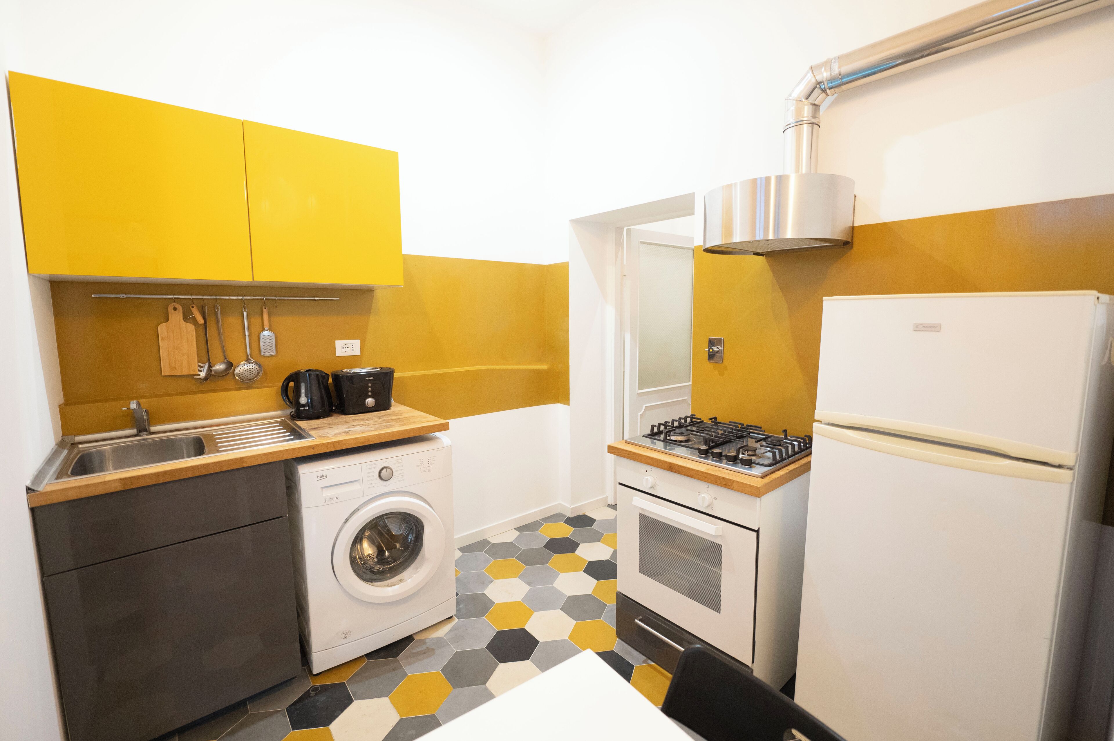Una cocina funcional con lavadora, estufa y refrigerador.