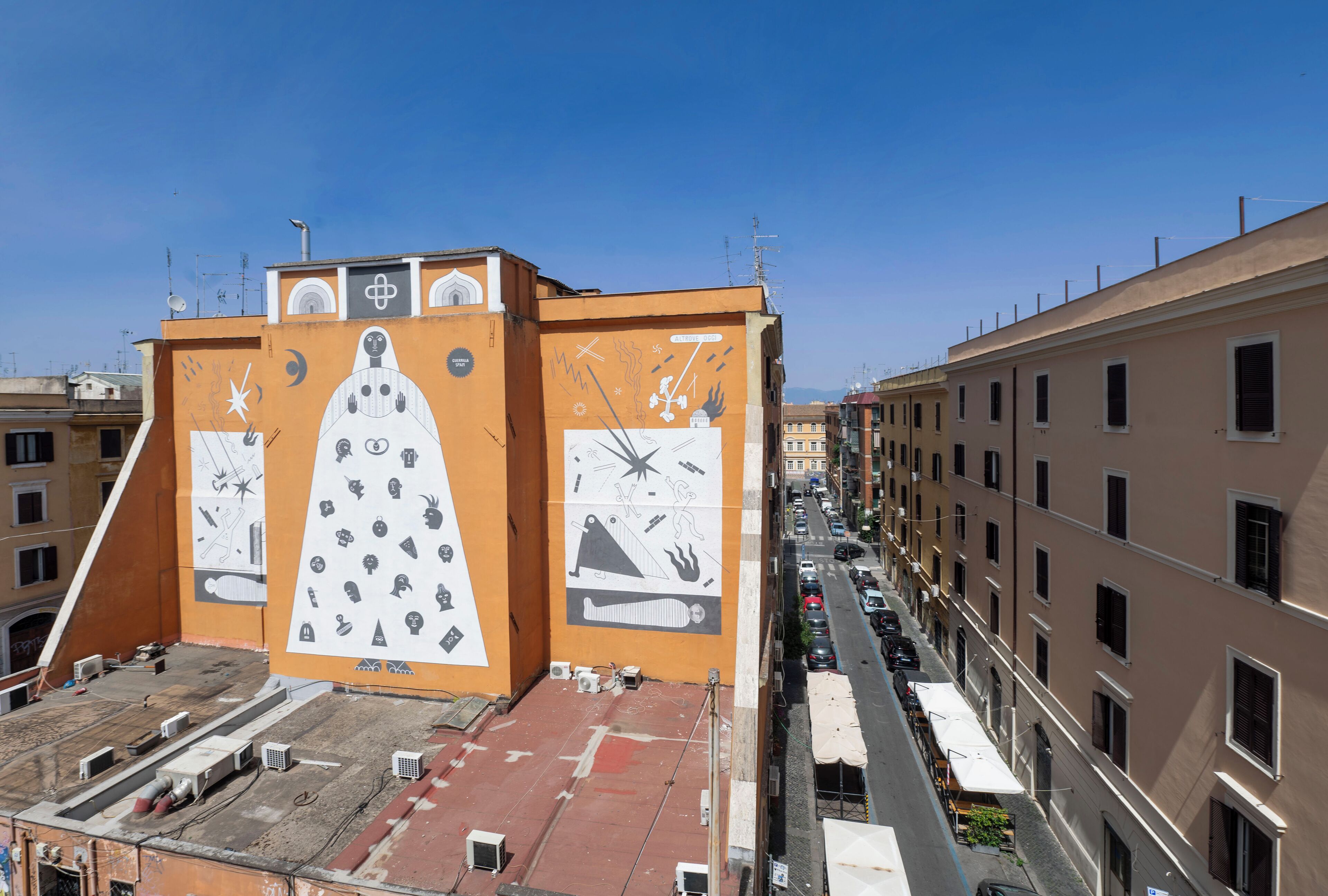 A building with a large mural on its facade, featuring various symbols and a prominent clock.