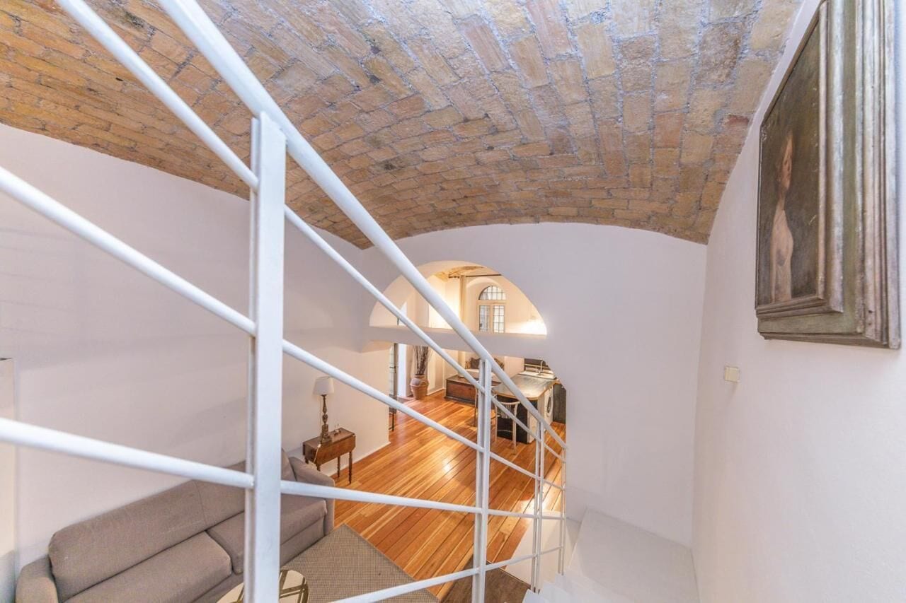 Quarto estilo loft com teto inclinado, escada e vista para um quarto.