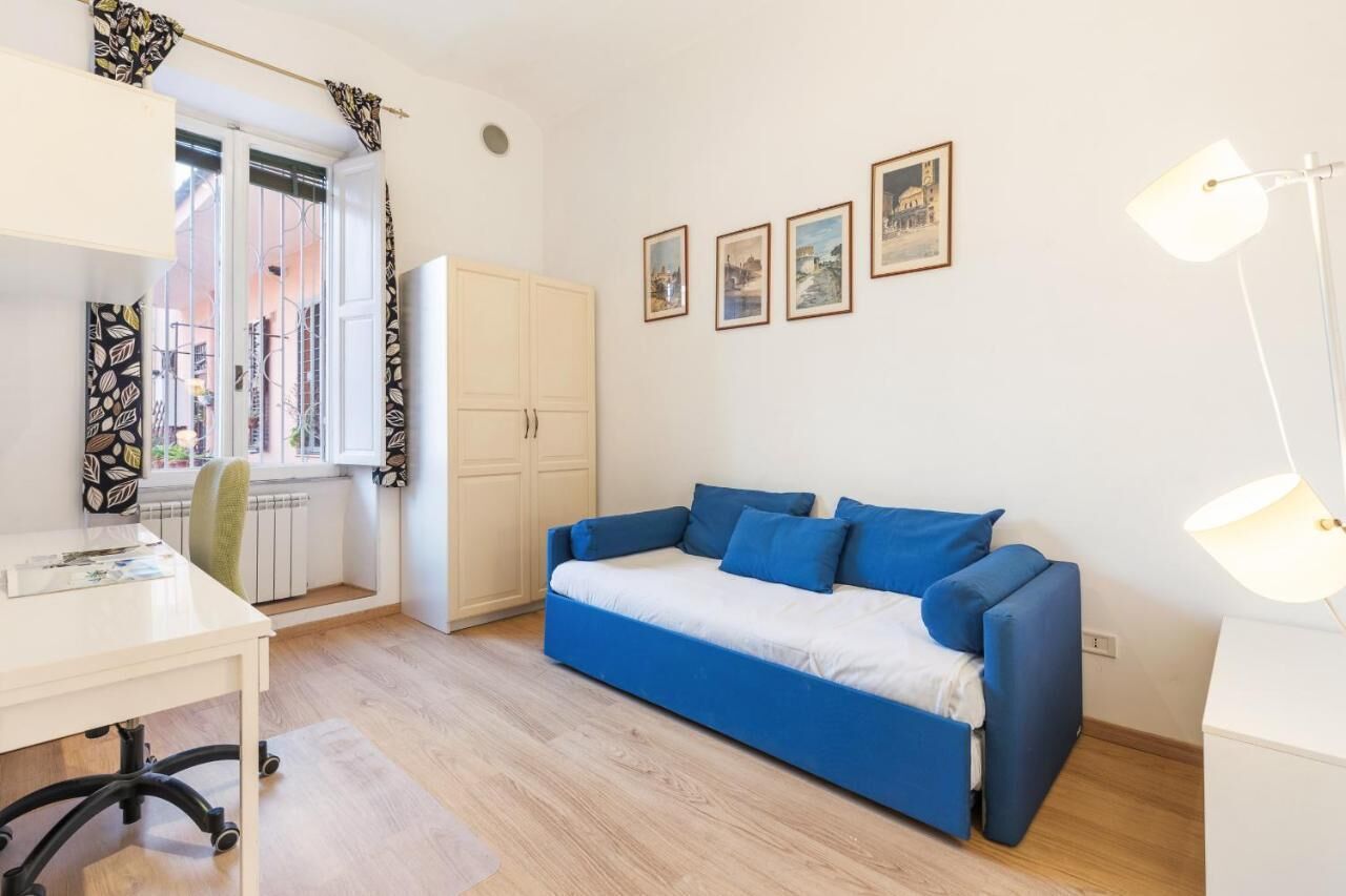 A modern room with a blue sofa, a white desk, and a window with curtains.