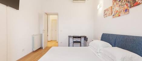 Un dormitorio con cama, escritorio y radiador.