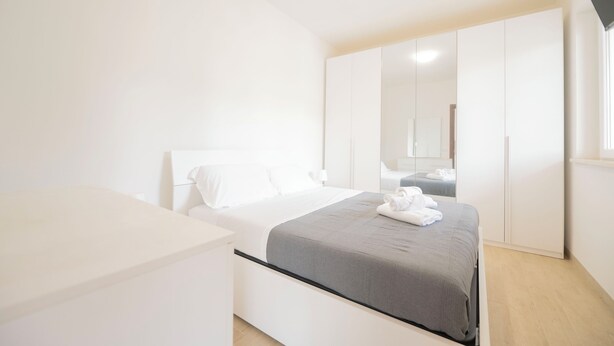 A modern bedroom with a bed, white wardrobe, and a bedside table. - Terraced Apartments By The Ancient Appian Way  (Rome)