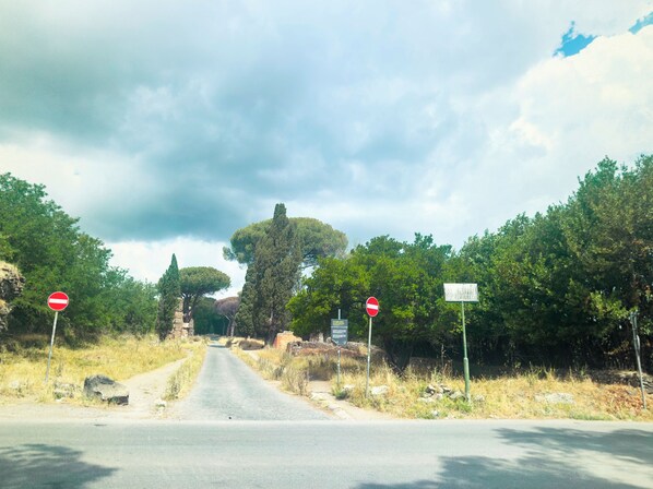 Una carretera con señales de prohibido el paso, rodeada de árboles y un cielo nublado.