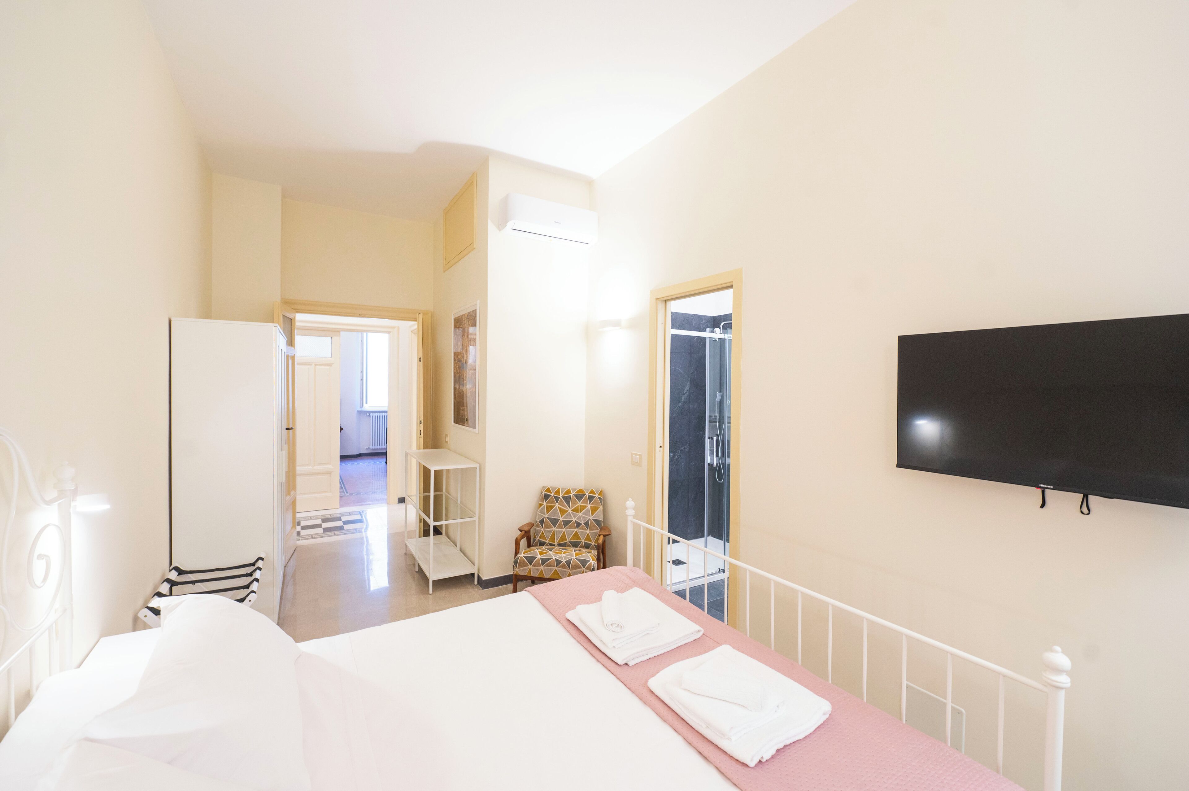 Ett hotellrum med en säng, en stol, en tv och en dusch.