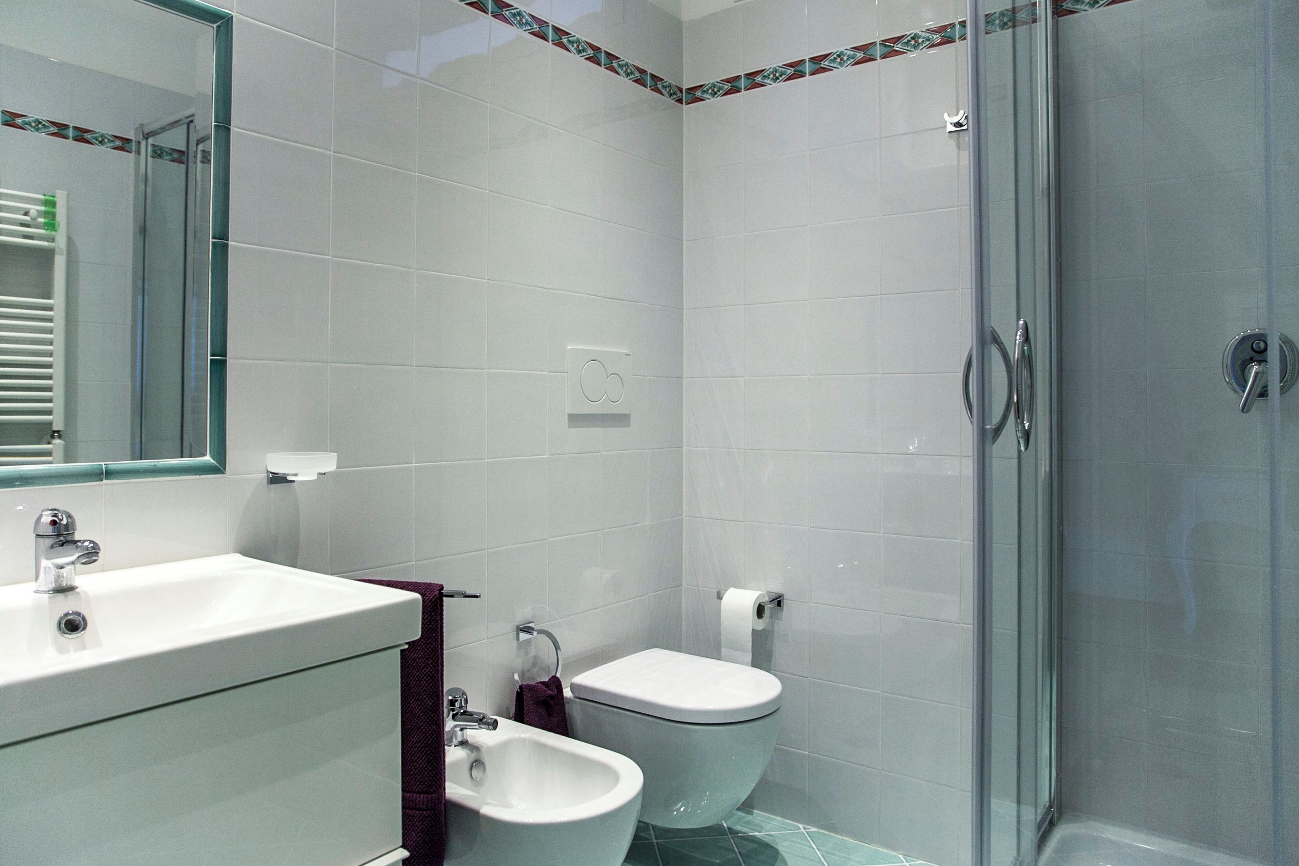 A bathroom with a sink, toilet, bidet, and glass-enclosed shower.