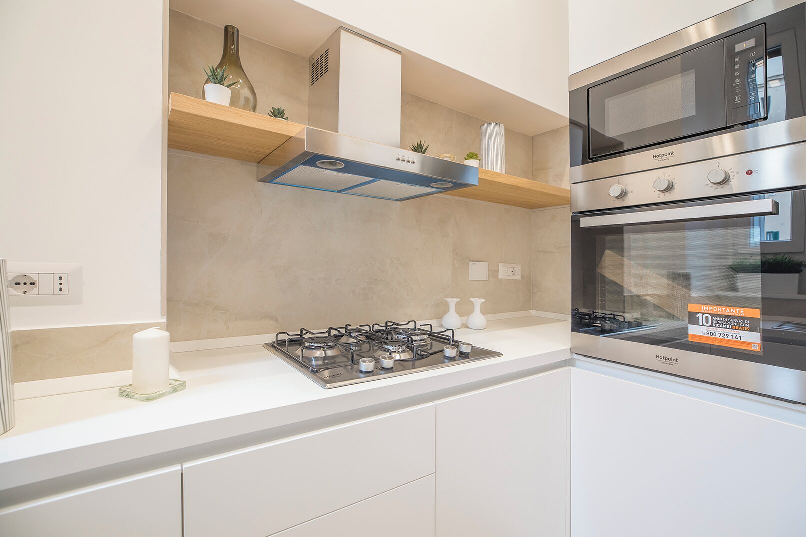Una cocina moderna con estufa a gas, horno integrado y microondas. Cuenta con gabinetes blancos y encimera de madera.