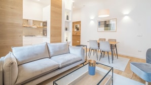 A modern living room with a sofa, a coffee table, and a dining area with chairs and a table.