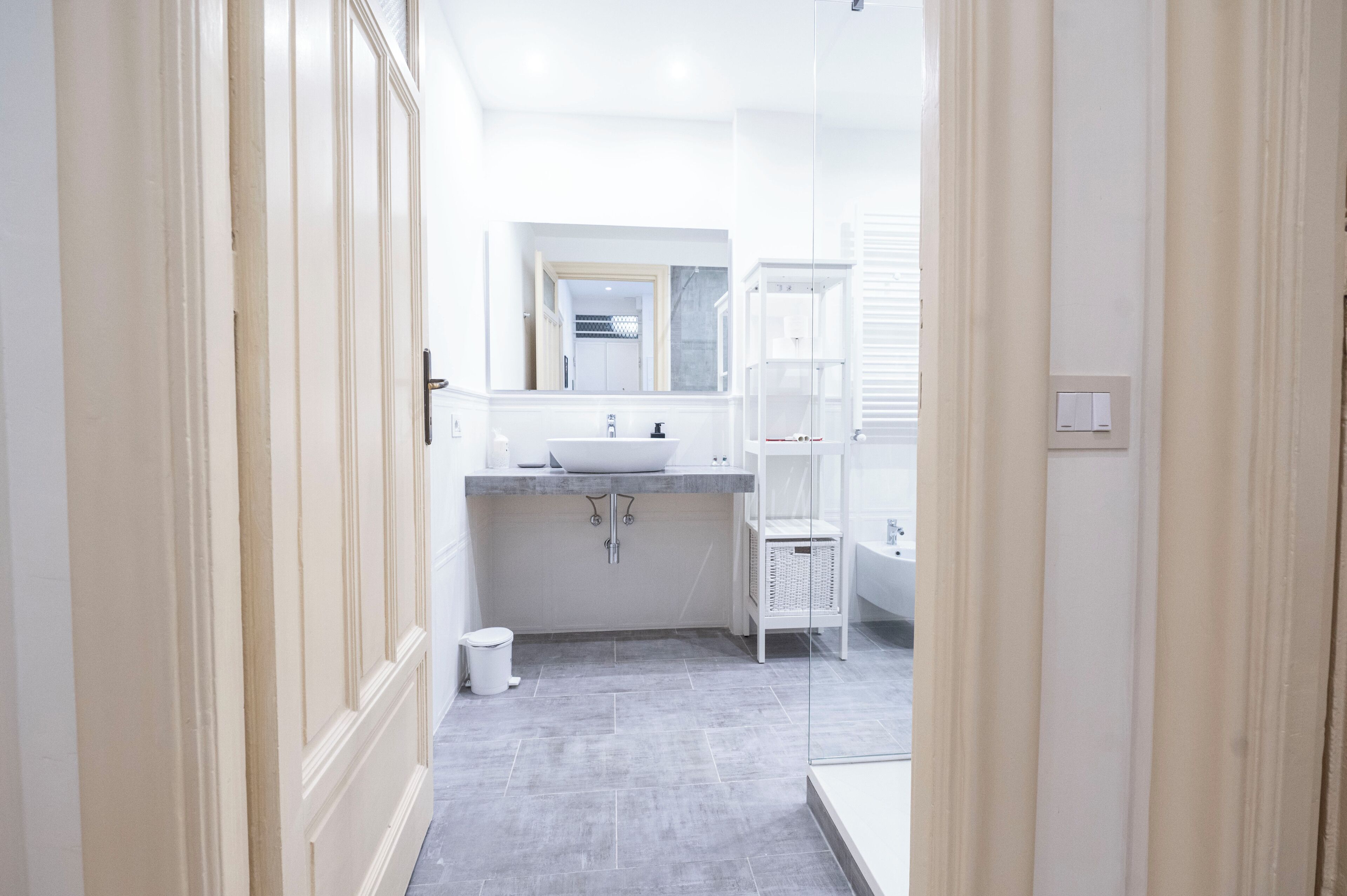 A modern bathroom with a large mirror, a sink, and a bathtub.