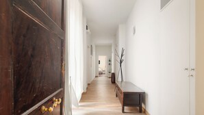 Un couloir doté d’un plancher en bois, d’un banc et d’une porte avec des poignées en laiton.
