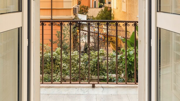 Un balcon ouvert donnant sur les bâtiments voisins et offrant une vue dégagée sur le ciel.