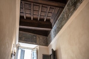A room with a sloped ceiling, a window with shutters, and a door. - Wonderful Apartment With Balcony In Piazza Margana (Rome)