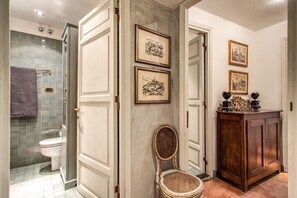 A bathroom with a glass shower enclosure, a toilet, and a wooden cabinet with framed pictures. - Wonderful Apartment With Balcony In Piazza Margana (Rome)