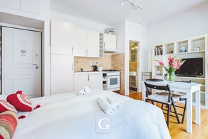 Een moderne hotelkamer met een bed, bureau, televisie en een kitchenette.