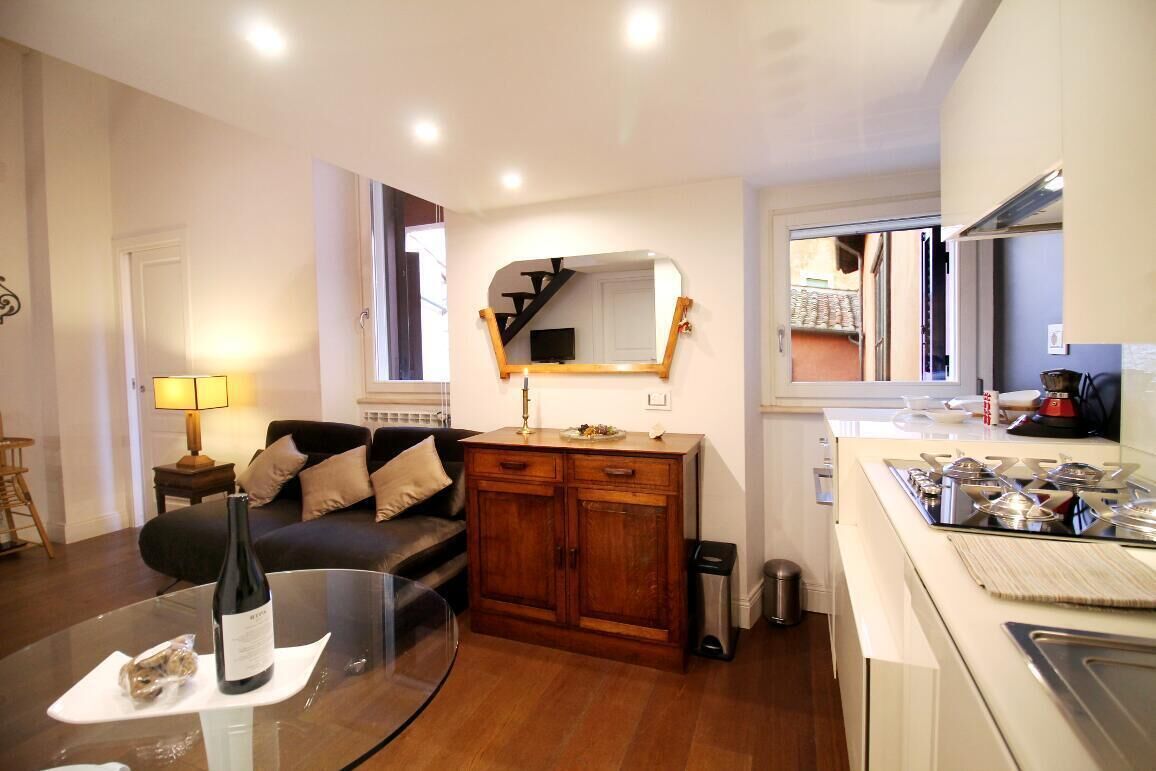 A compact living space with a kitchenette, a sofa, a dining table, and a mirror.