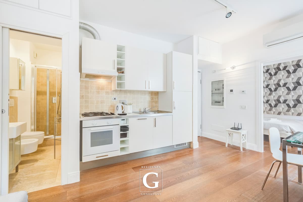 A modern kitchen with white cabinets, a built-in oven, and a tiled backsplash.