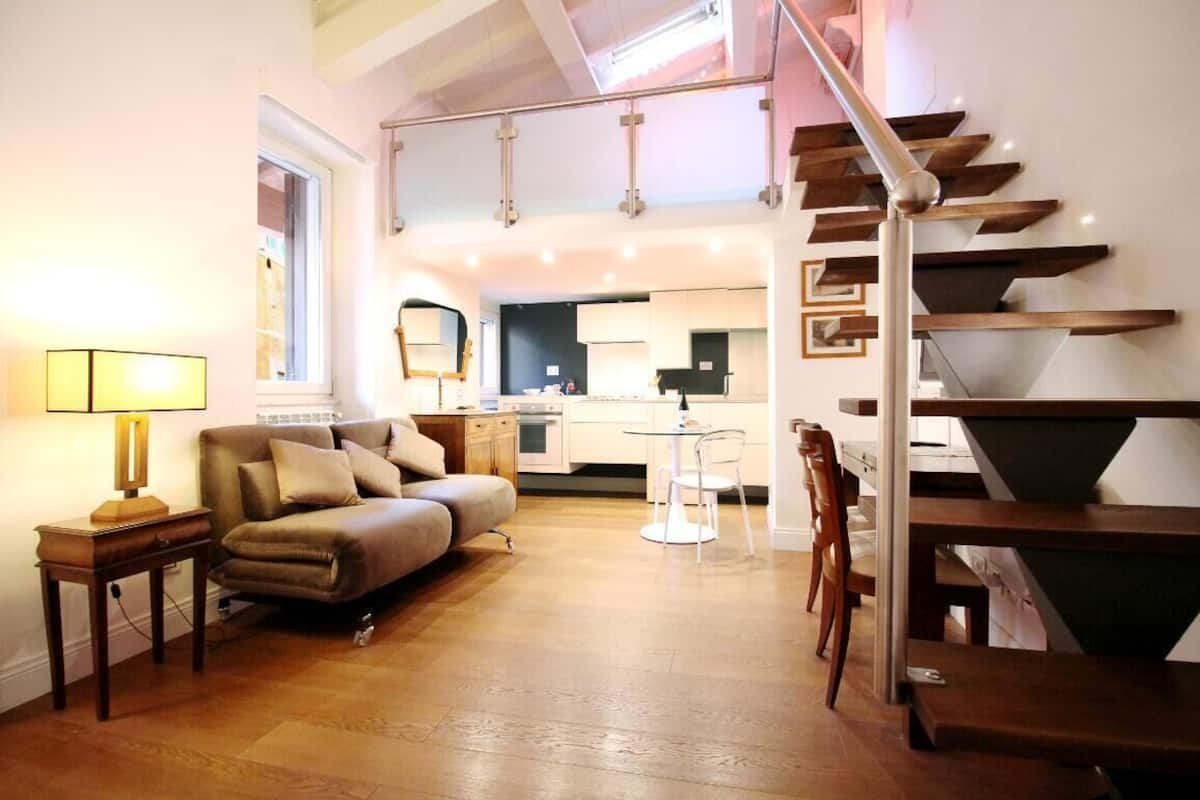 A modern living room with a sofa, a small table, and a staircase leading to an upper level.