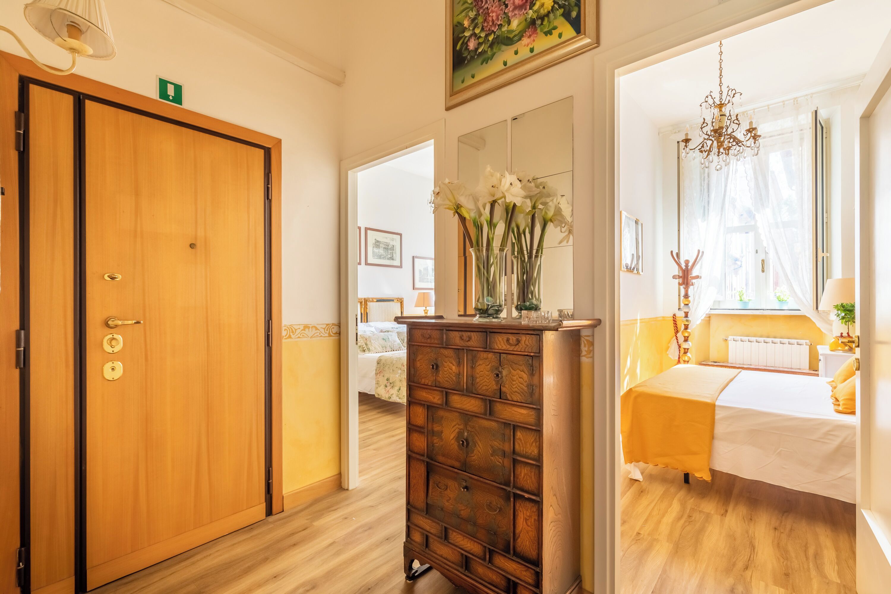A room with a wooden wardrobe, a dresser, and a bed with a yellow bedspread.