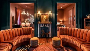 A cozy room with a fireplace, two leather sofas, and a patterned rug. - Iconic Mansion w/Private Pool & Spa, Walk Downtown (New Orleans)