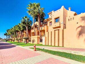 A row of palm trees and a building with a flat roof and beige walls. - Beach location, wifi, parking, communal pool (Los Alcazares)