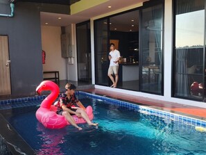 Piscina com uma pessoa sentada em um boi de flamingo rosa.