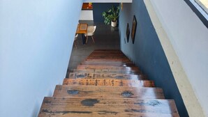 A wooden staircase leading to a room with a blue wall and a small table with chairs. - Brick Box Pool Villa & Café (Doi Saket)