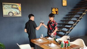 A dining area with a wooden table set for two, a staircase, and a framed picture on the wall. - Brick Box Pool Villa & Café (Doi Saket)