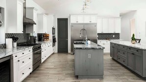 A modern kitchen with white cabinetry, a central island, and a stainless steel refrigerator. - Top-Notch Villa in Central Scottsdale (Scottsdale)