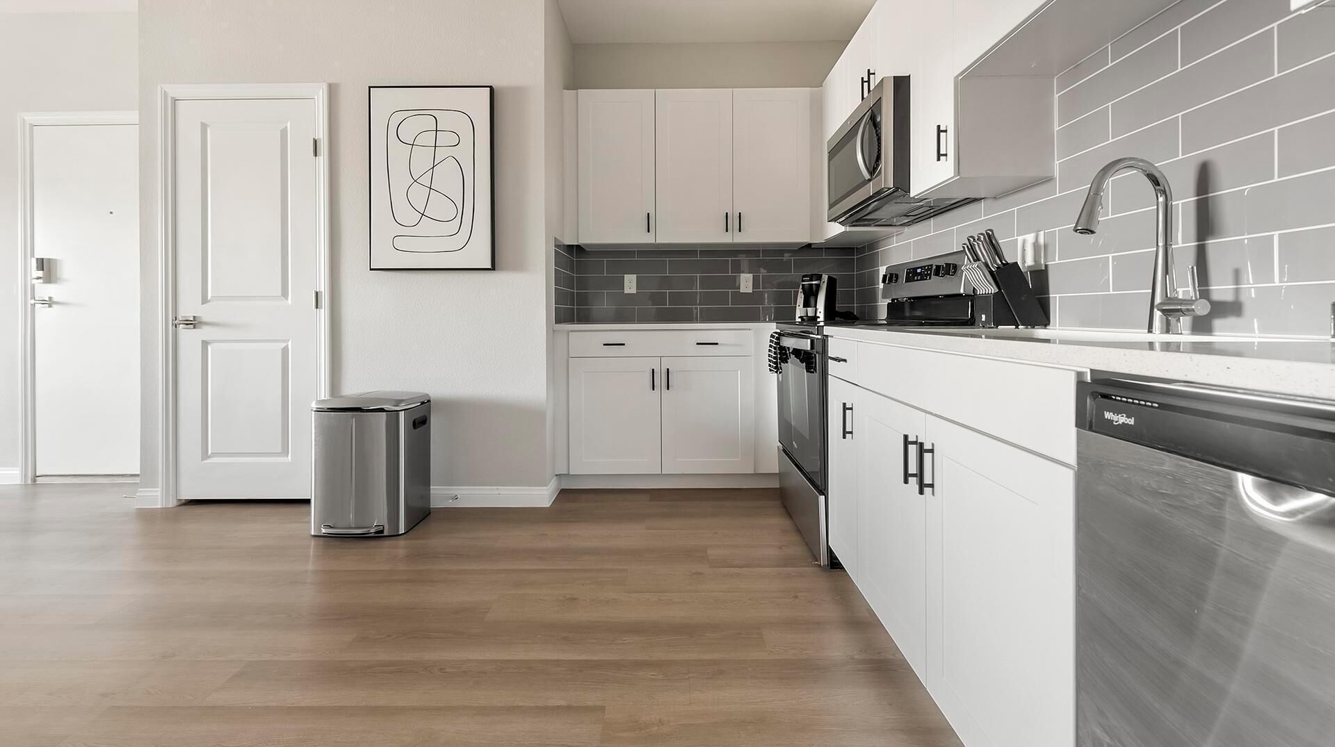 Een moderne keuken met witte kasten, een roestvrijstalen vaatwasser en een magnetron.