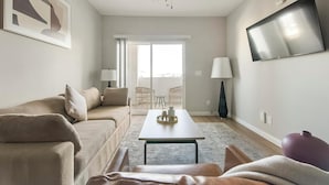 Una sala de estar moderna con un sofá color beige, una mesa de centro y un televisor montado en la pared.